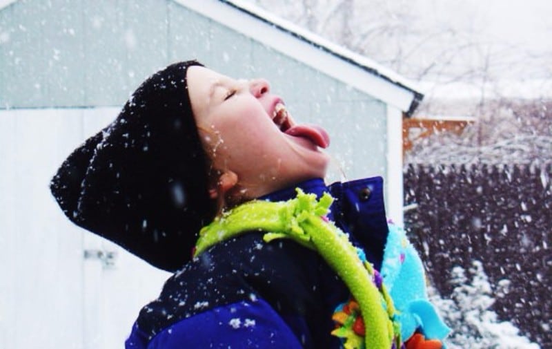 Criança com boca aberta comendo neve
